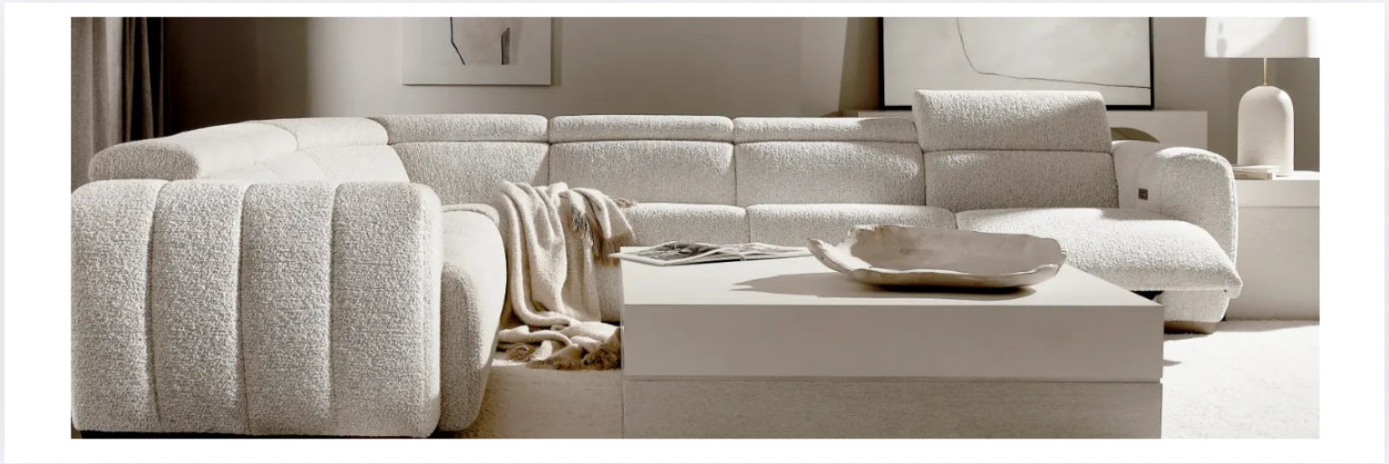 Contemporary living room with a curved ivory boucle sectional sofa and modern low-profile coffee table, styled with neutral decor and cozy throw blanket