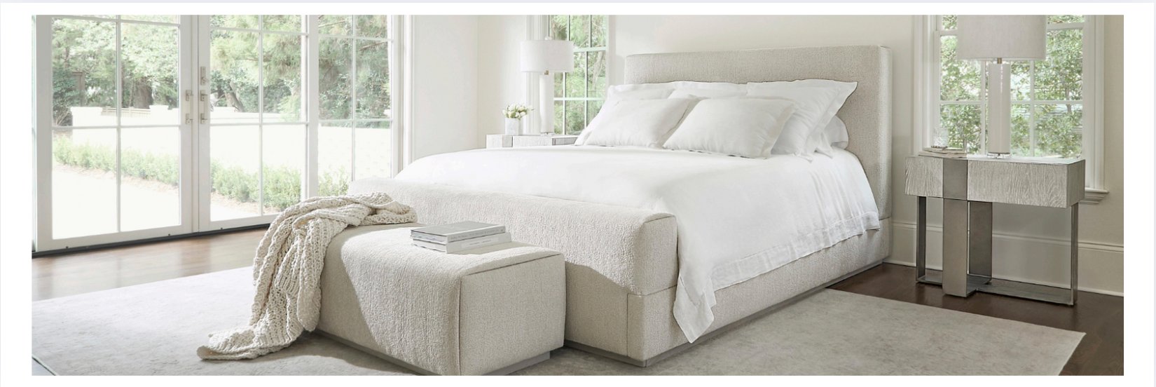 Bright and modern bedroom featuring an upholstered platform bed with white bedding, flanked by mirrored nightstands and styled with a boucle bench and cozy throw blanket
