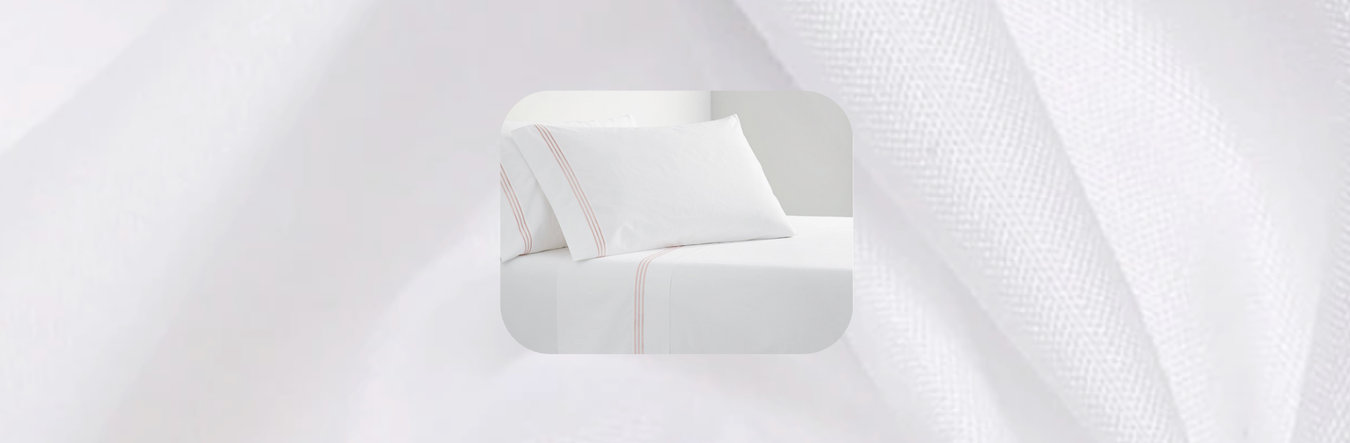 White bed sheets with blush pink double-line embroidery on pillowcases and flat sheet, displayed on a neatly made bed with soft white textured background