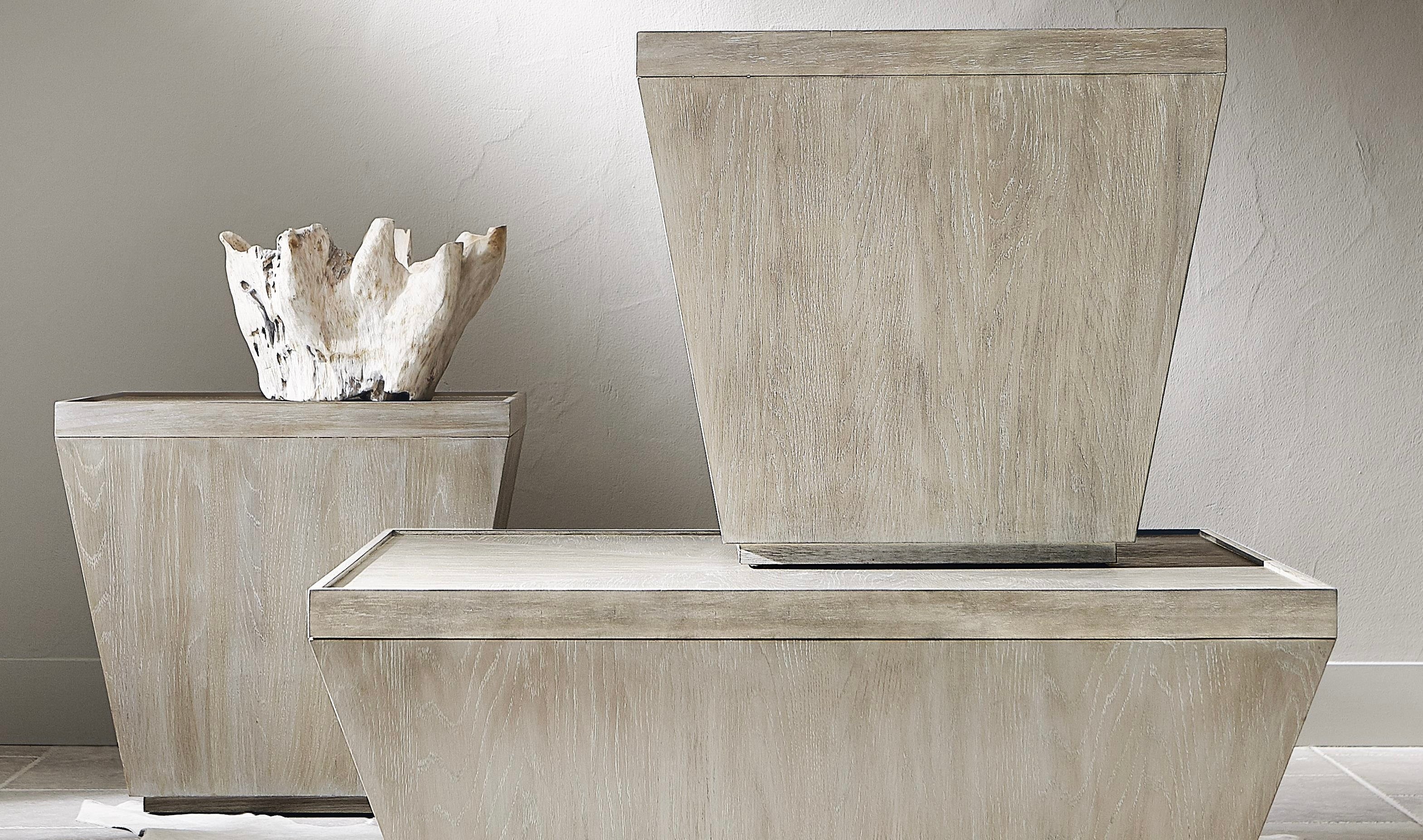 Modern geometric wood coffee table and matching end tables in a light natural finish, styled with a white sculptural decor accent against a neutral wall