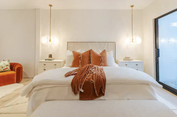 Bedroom by Marisol Gullo Interiors with rust pillows, pendant lights, and neutral décor.