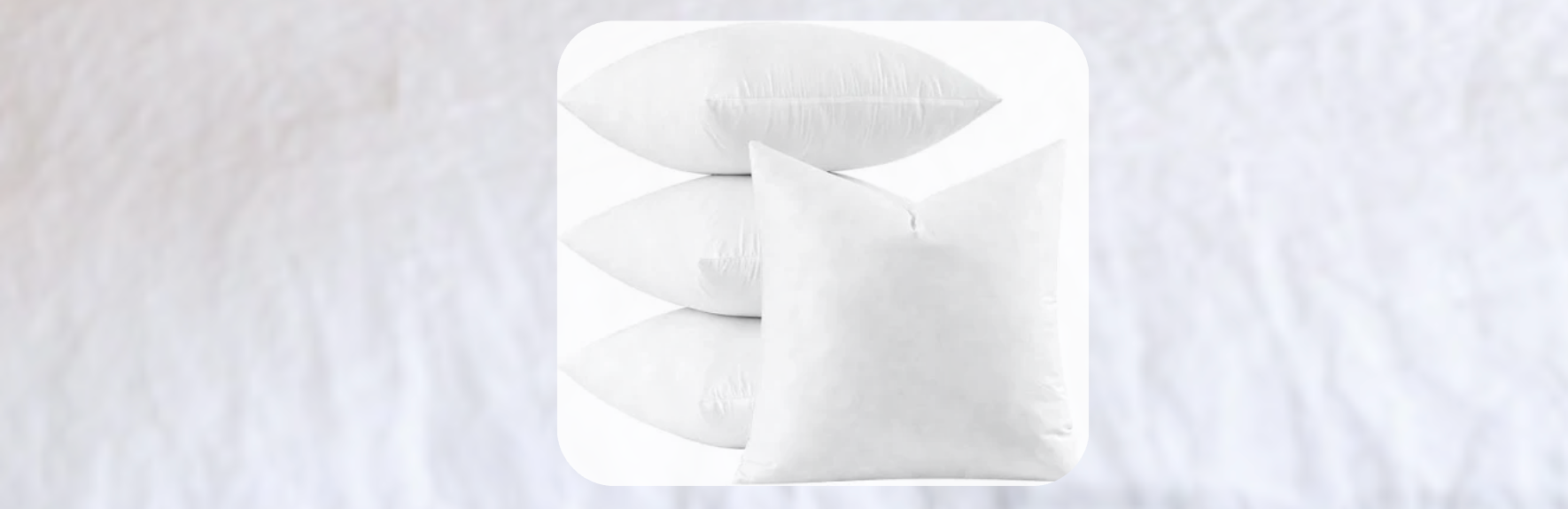 Set of white bed pillows in various shapes and sizes, stacked neatly on a white bed with soft natural lighting and minimal styling