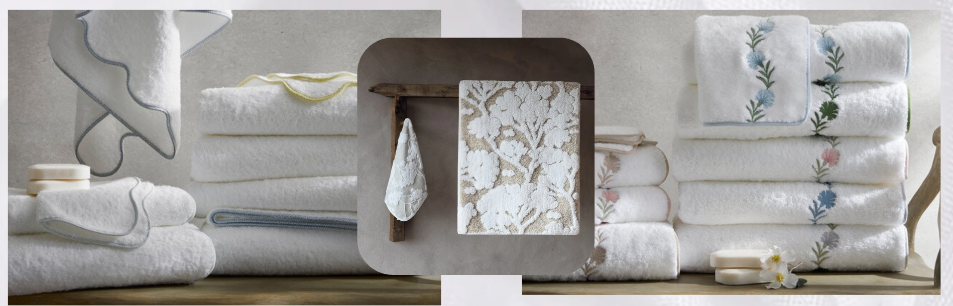 Stacked luxury bath towels in soft white with embroidered and scalloped edges, displayed neatly on wooden shelves with folded linens, decorative florals, and a modern towel hook in a serene, spa-like setting